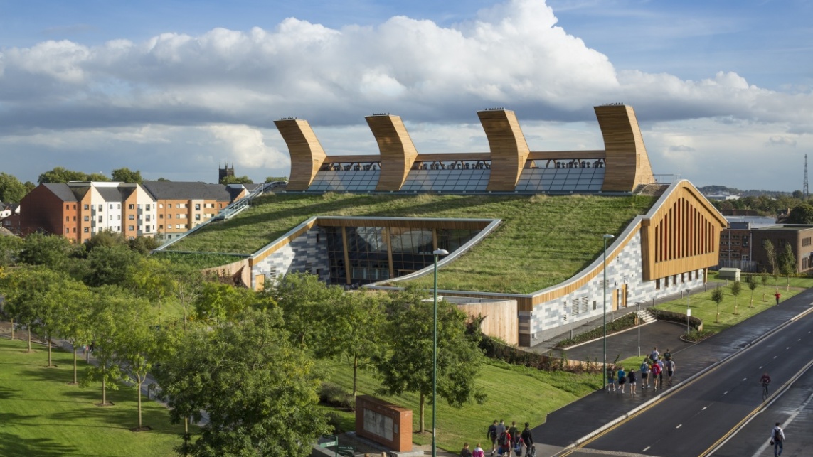 an aerial shot of a eco-friendly campus building, with grass growing on the roof