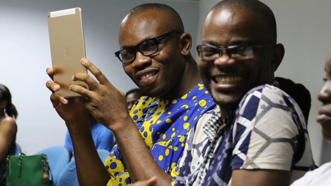 people in glasses smiling with a mobile tablet