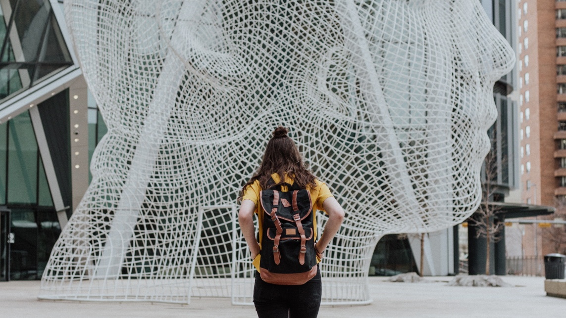 Back of woman with backpack in front of sculpture