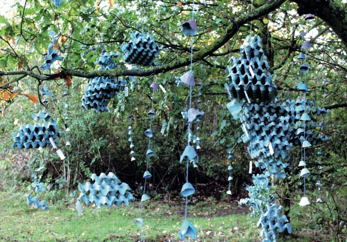 Installation art piece featuring sculptures made from blue egg crates hanging from trees