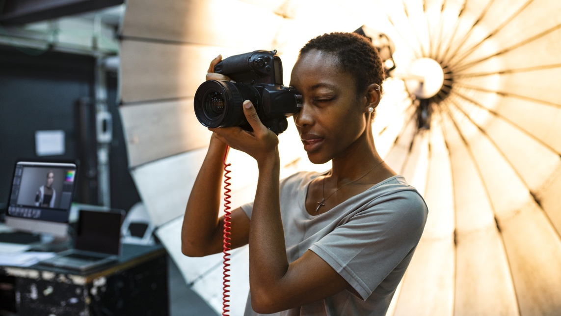 Young photographer standing in front of a reflective umbrella