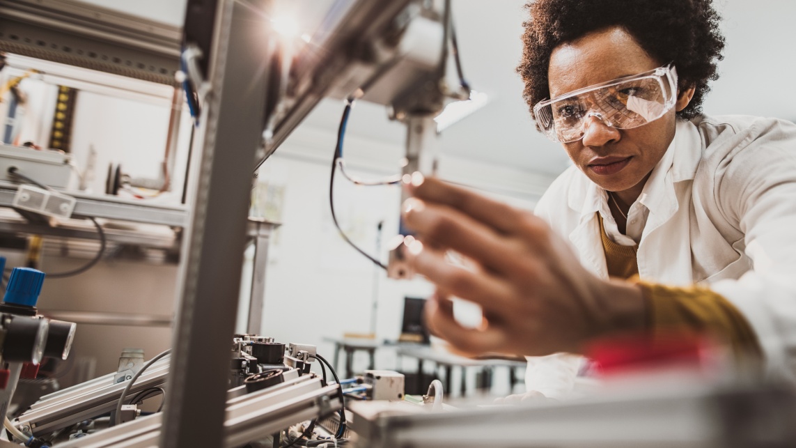 Black female engineer working on industrial machine in a laboratory