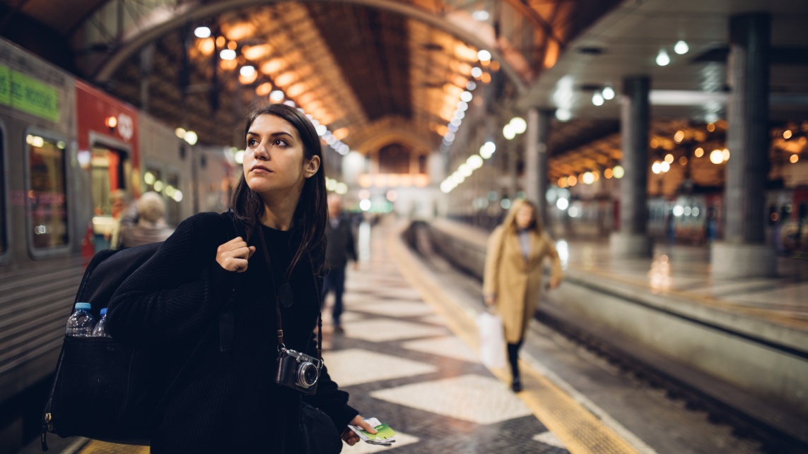 Female traveler searching for directions,waiting for the train/tram,using transportation in foreign country.Urban tourism.Low budget cheap ticket backpacking