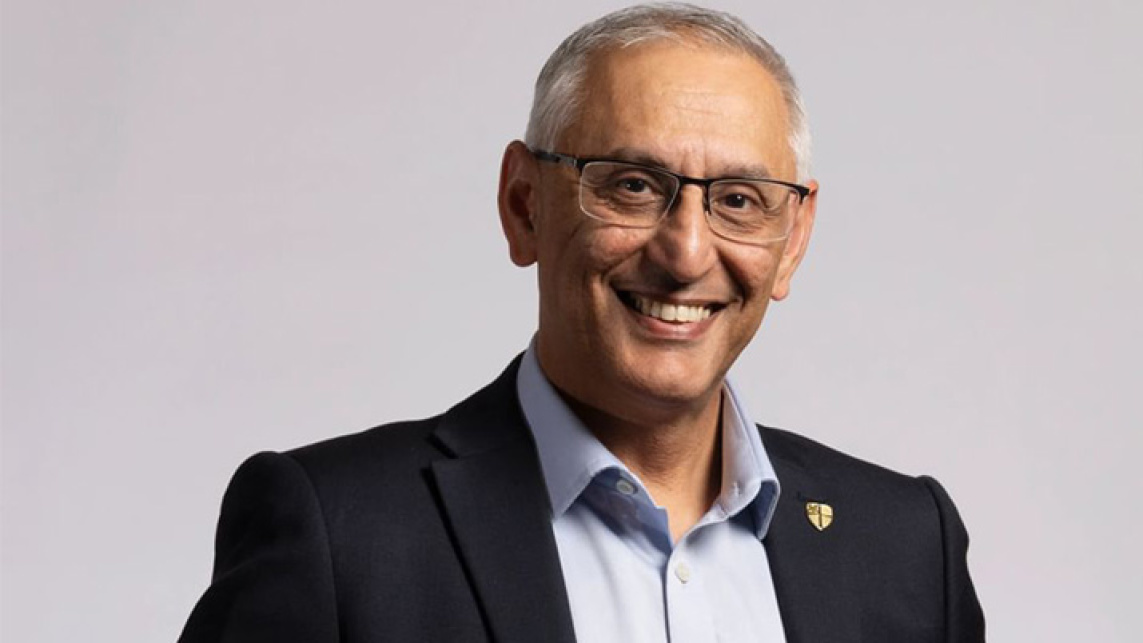 Dr Shaid Mahmood, Pro Vice-Chancellor EDI, Durham University stands against a plain background. Dr Mahmood wears a black suit and light blue shirt.