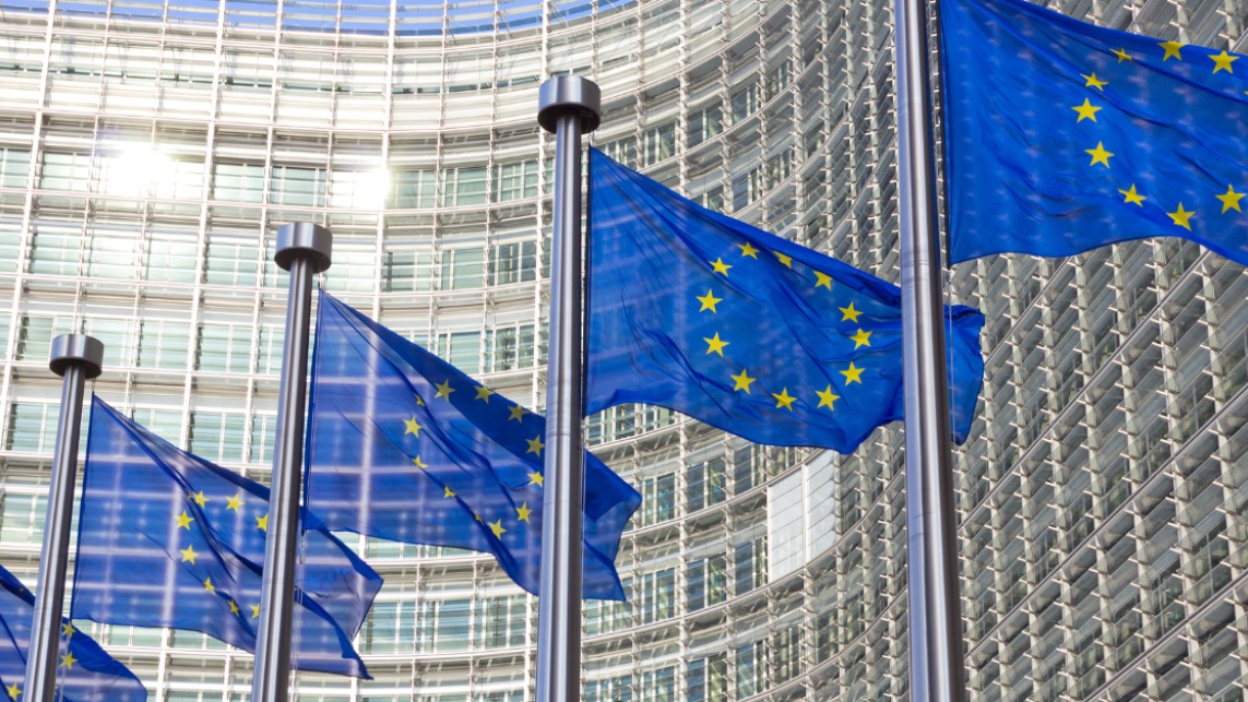 Five EU flags at full mast, blowing in the wind.