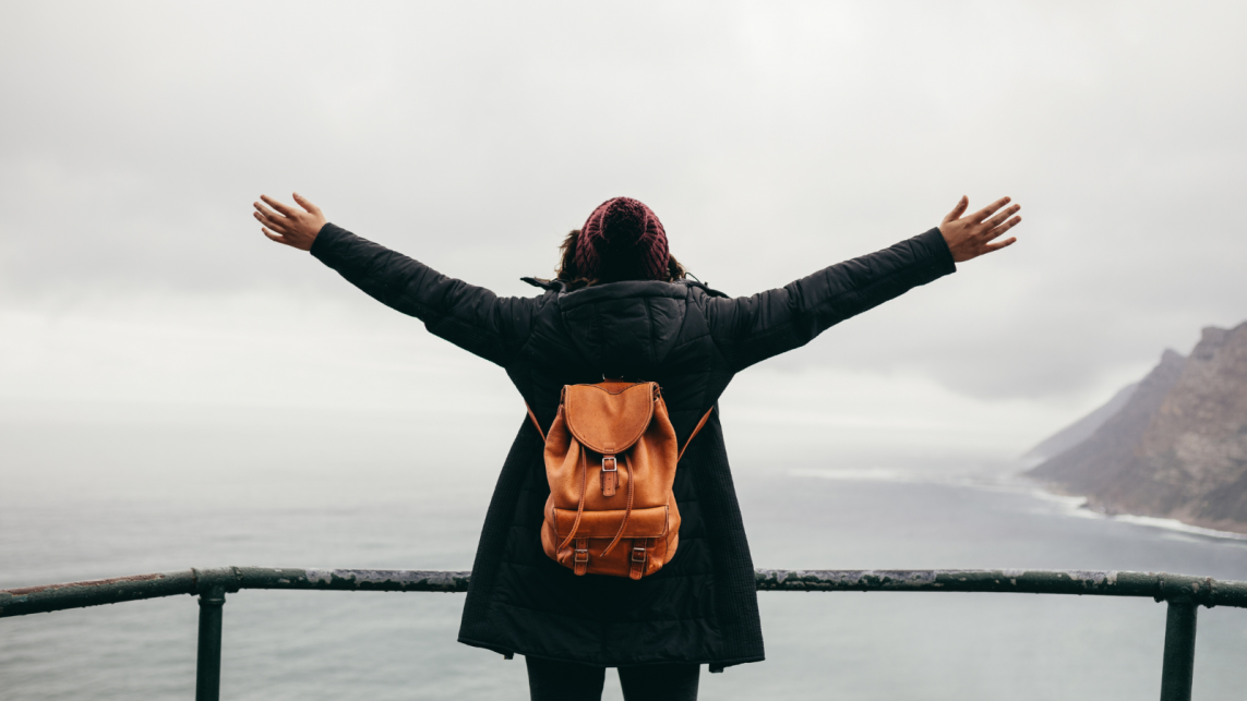 a person with their hand wide open looking at the sea
