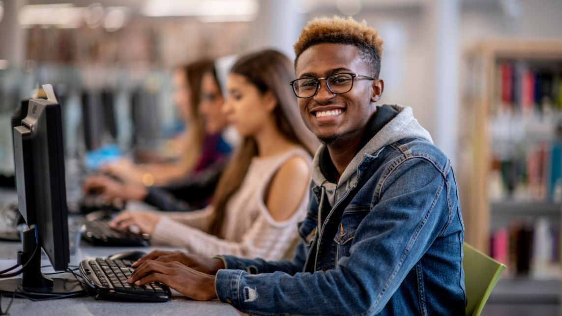 student working on a computer and smiling