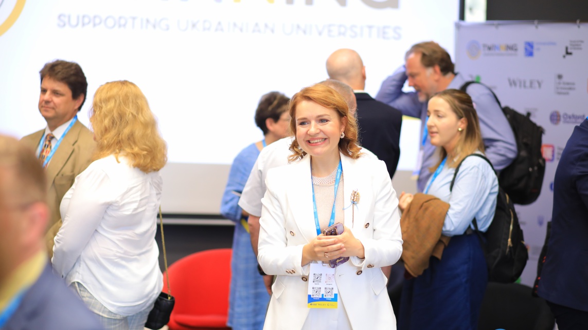 Delegates of the UK-Ukraine Second International Twinning Conference gathered at the conference with the Twinning scheme logo displayed on a screen behind them.