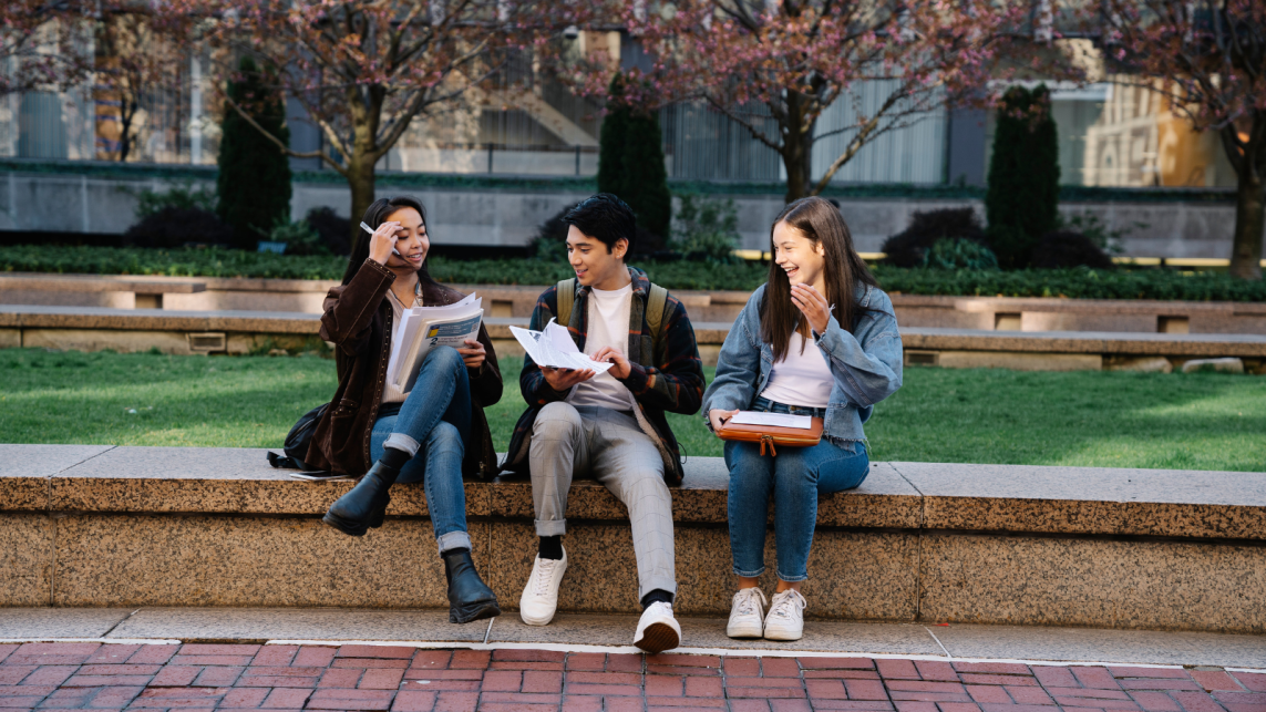 A group of three students socialising in a university campus