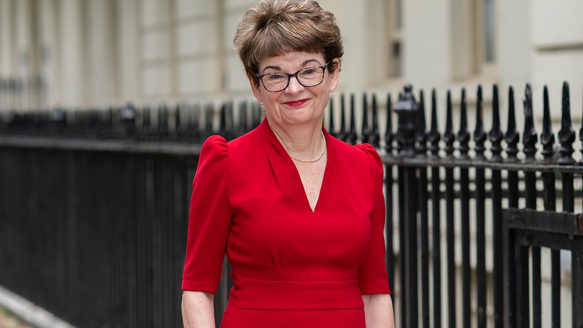 Professor Sally Mapstone DBE smiling outside in Bloomsbury wearing a red dress