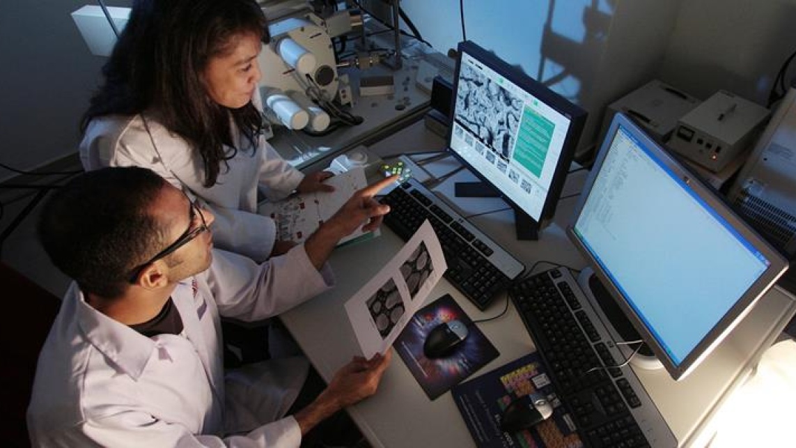 two researchers working in a lab with laptop screens in front of them