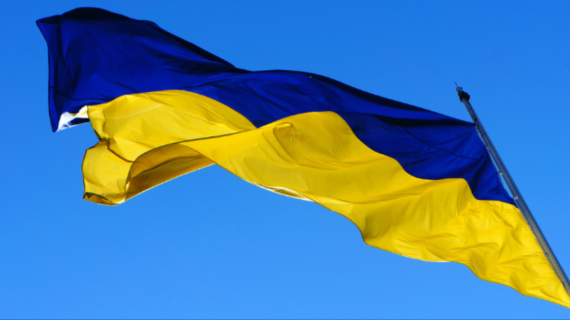 Ukraine flag blowing in the wind against the backdrop of a blue sky.