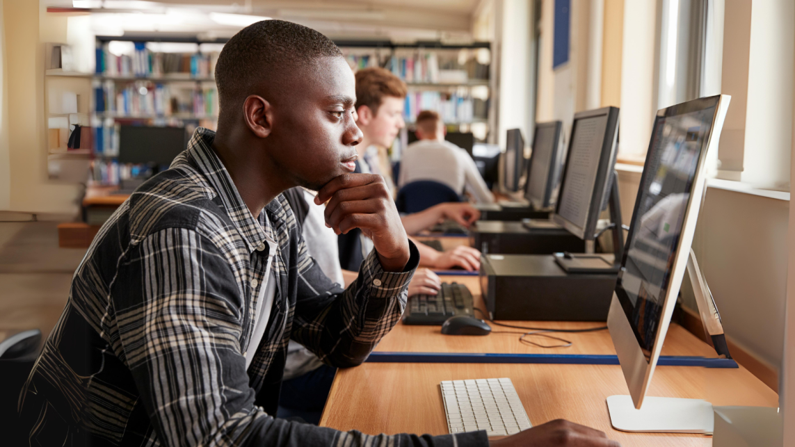 A student reading from his monitor screen in a library