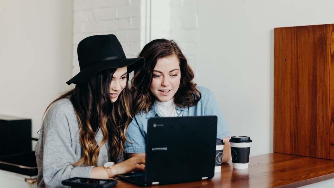 Two students look at a laptop