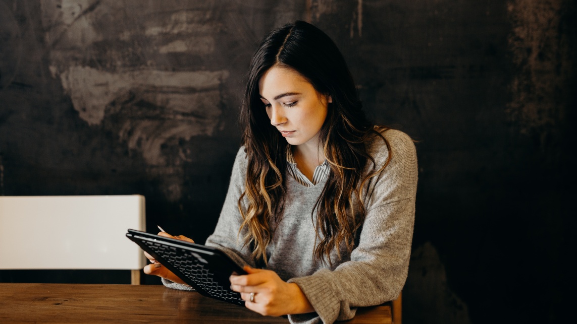 Woman at desk holding tablet concentrating