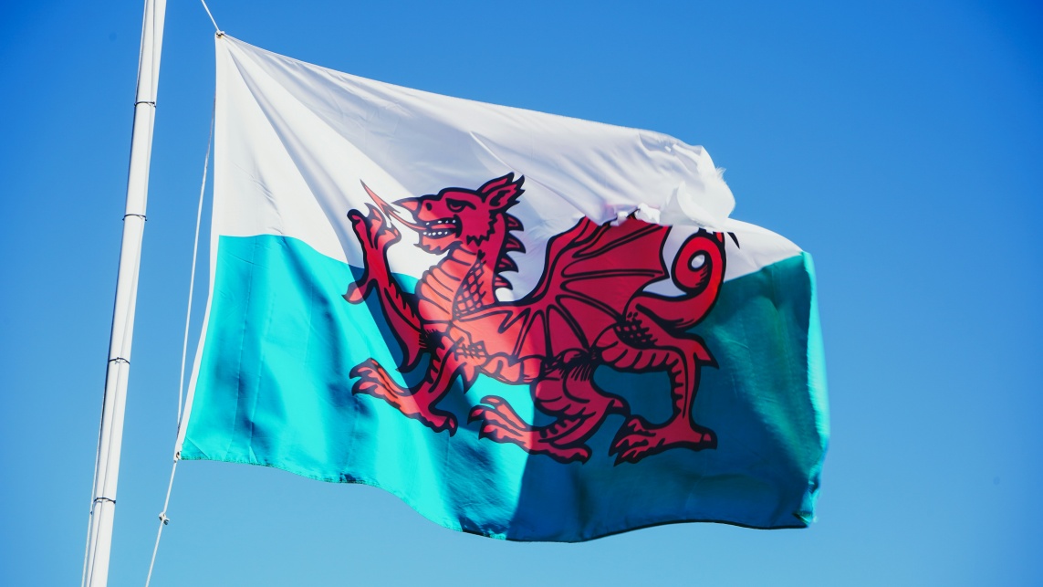 The Welsh flag against a backdrop of a blue sky, hung on a flagpole