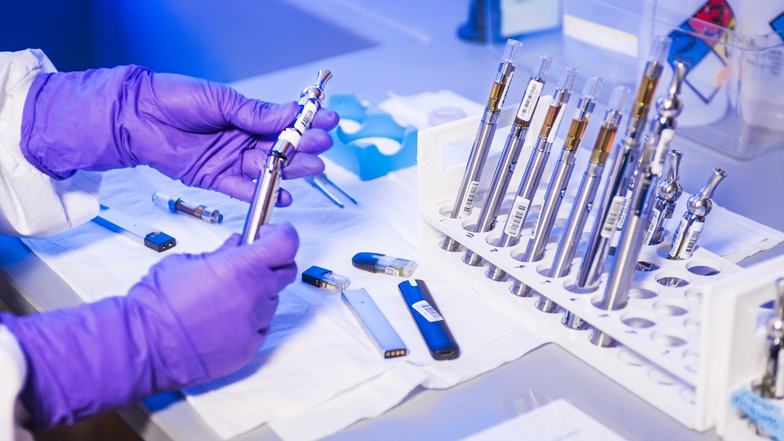 A pair of hands in gloves handling test tubes 