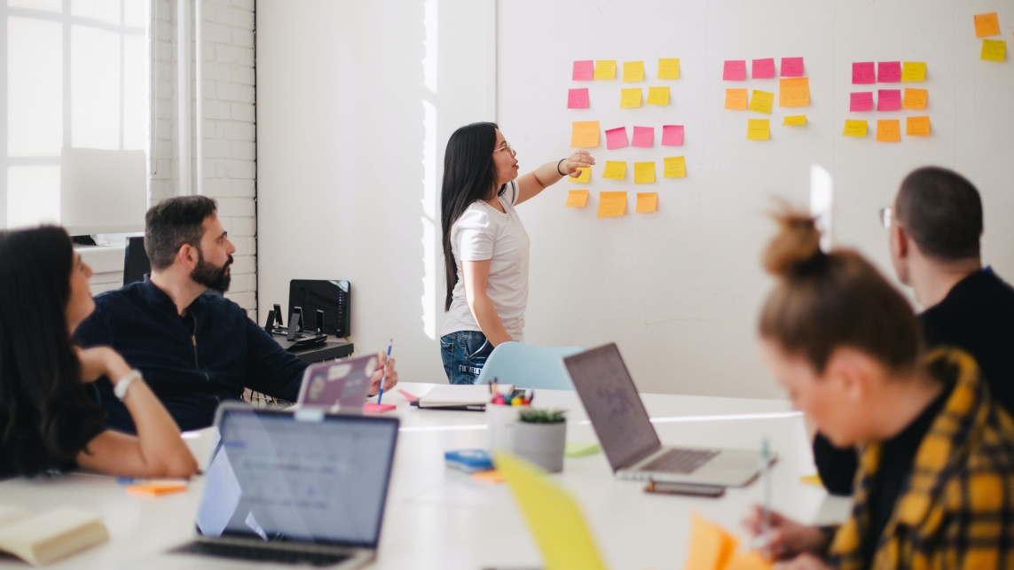 Group of people working together with post-it notes and laptops