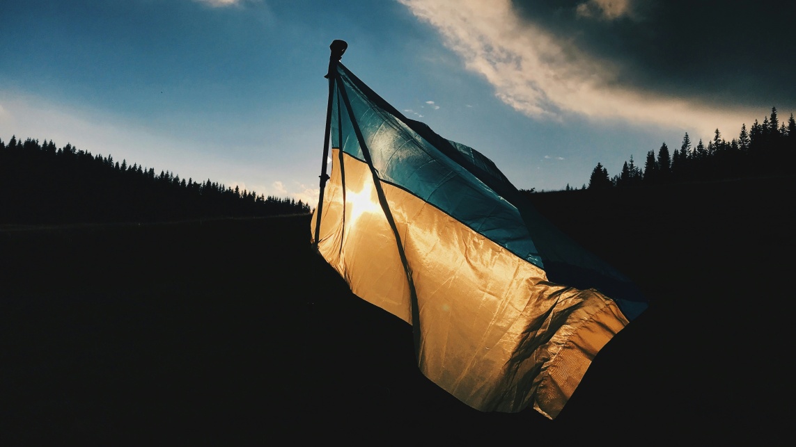 The Ukraine flag, in low light, against the sun