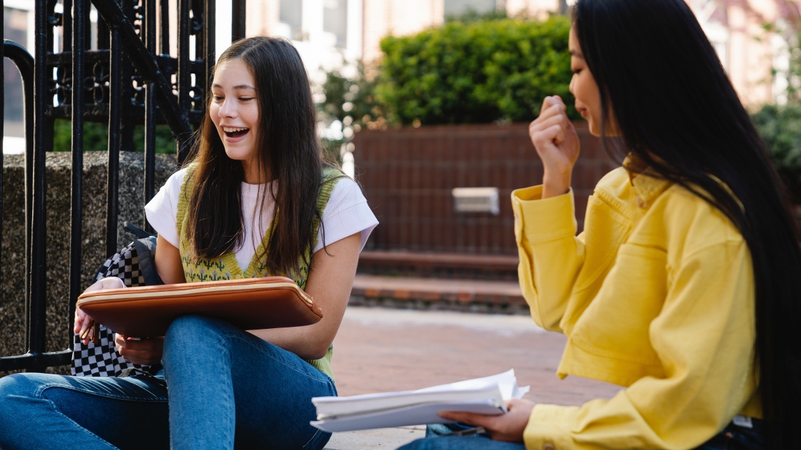 Two students sitting and chatting outside