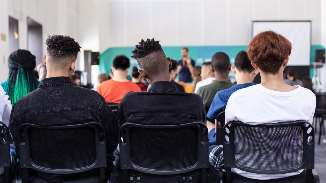 Students sitting in a classroom in a row of chairs 