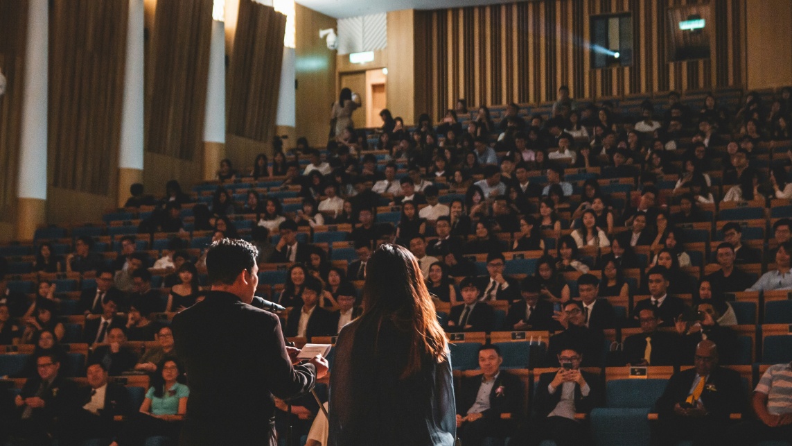 Two speakers at a conference speaking to attendees