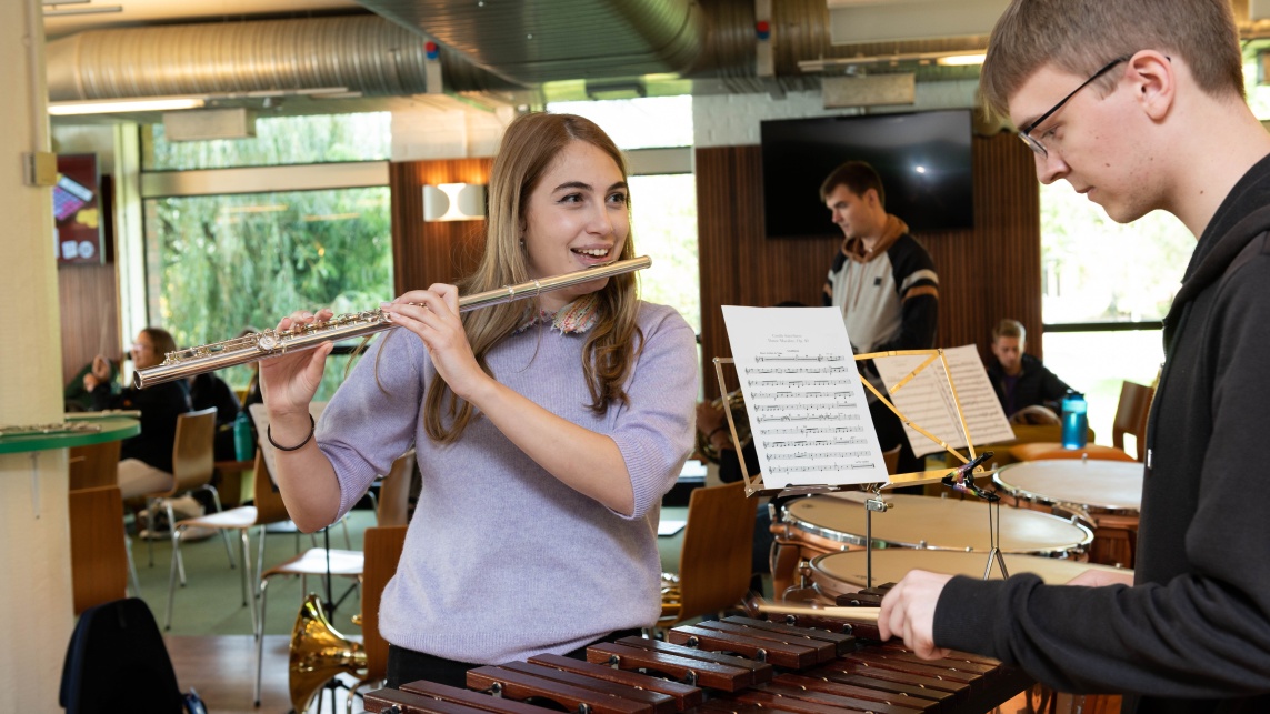 A student practises the flute and another practises playing the xylophone for a university orchestra