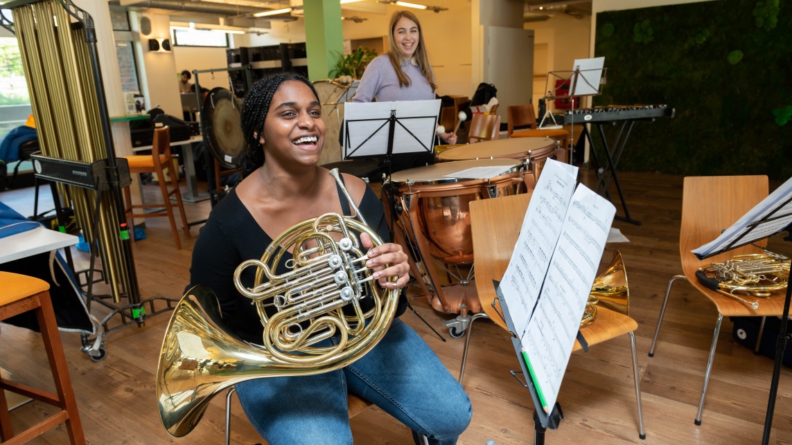 A student practises the french horn for a university orchestra
