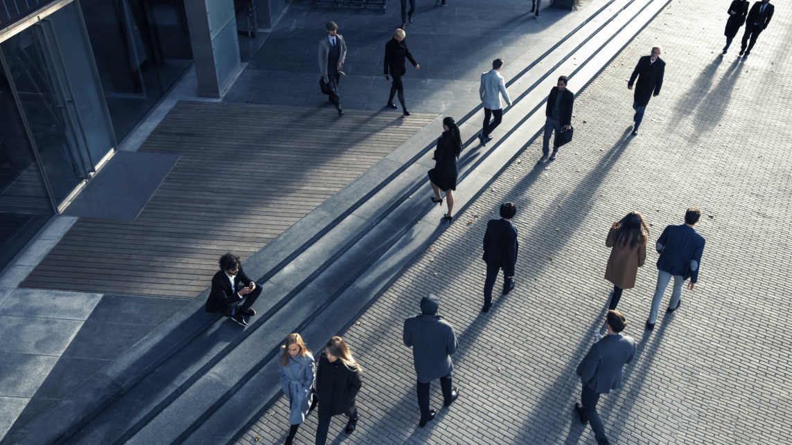 View from above of business people commuting to work in the morning on a sunny day on foot. Pedestrians are dressed smartly.