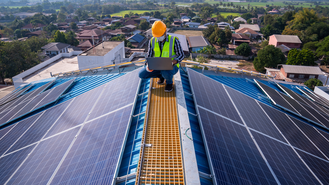 A construction worker setting up solar panels on housing 