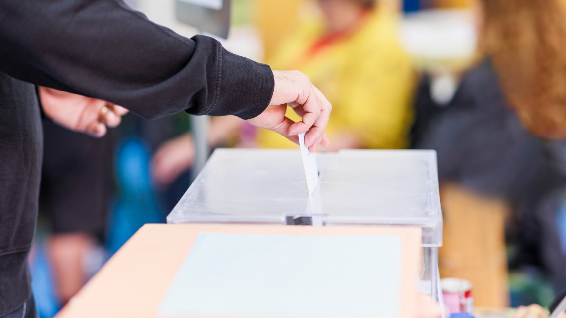 Anonymous voter putting their vote into a box.