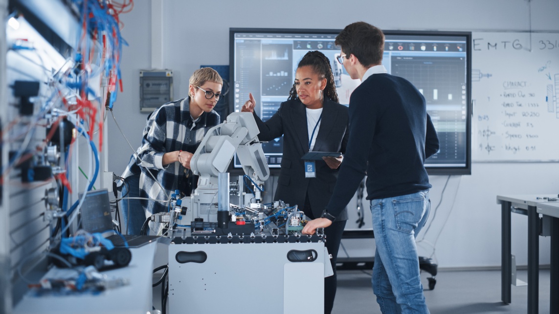 Colleagues work together on machinery in a lab