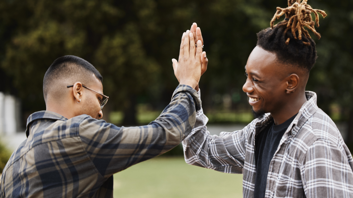 Two students high five in a park 