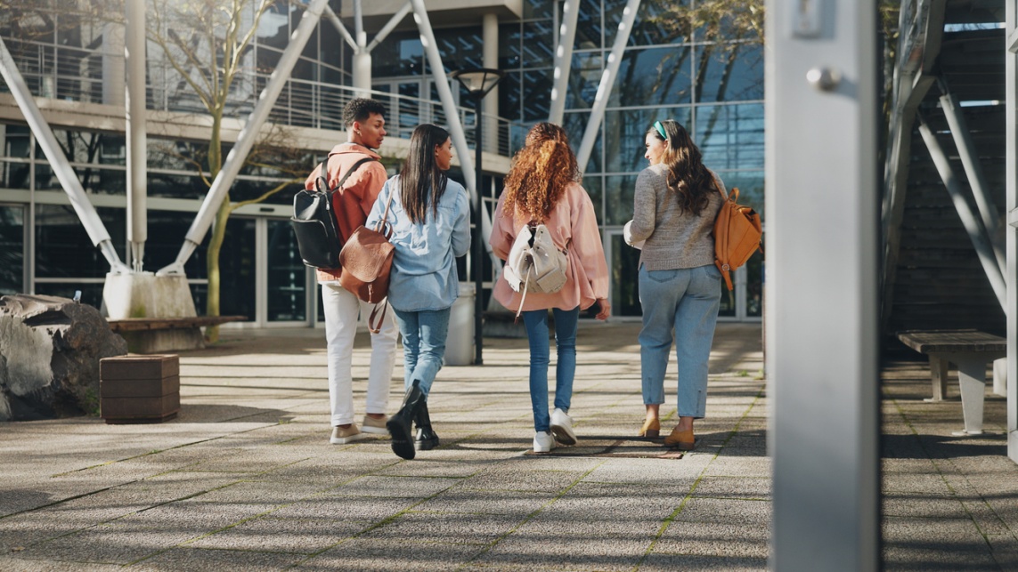 Students walking at college to class. The students wear backpacks. 