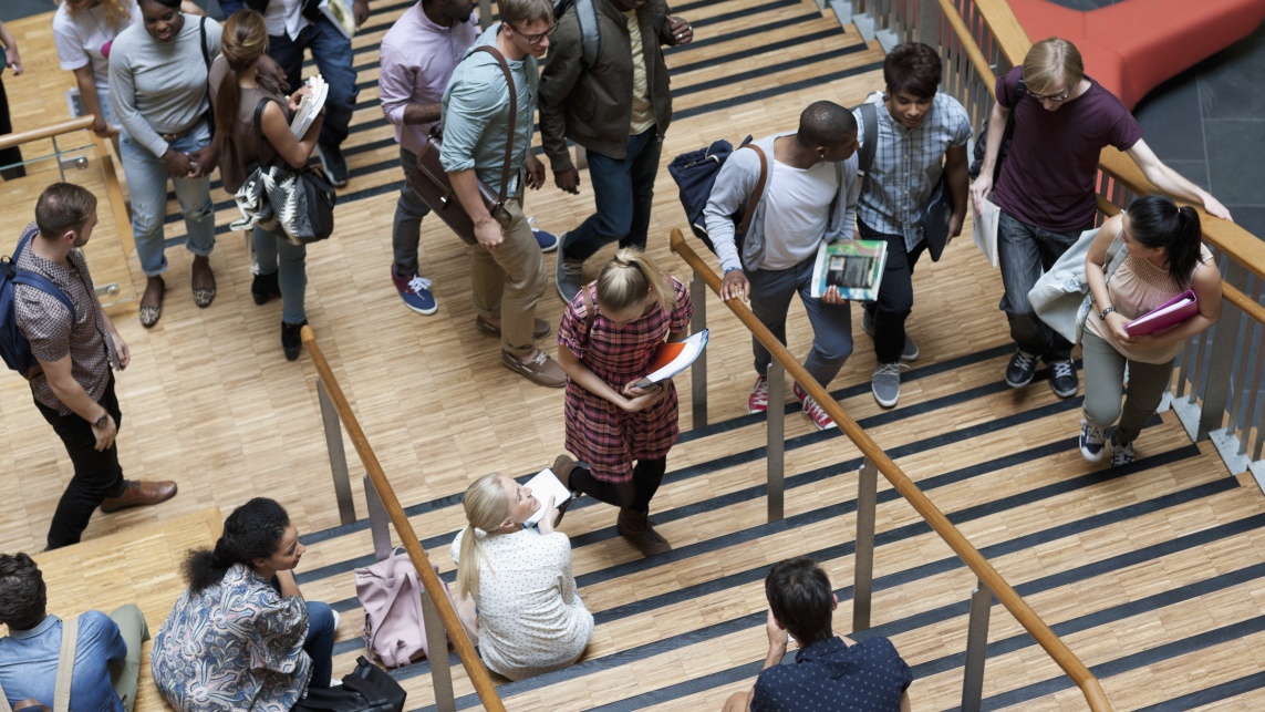 Elevated view of university students walking up and down stairs at a university campus.