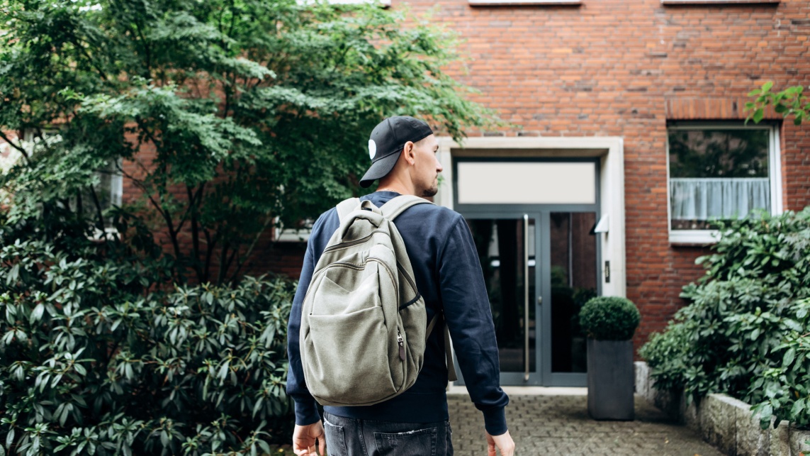Student wearing backpack returning home to flat