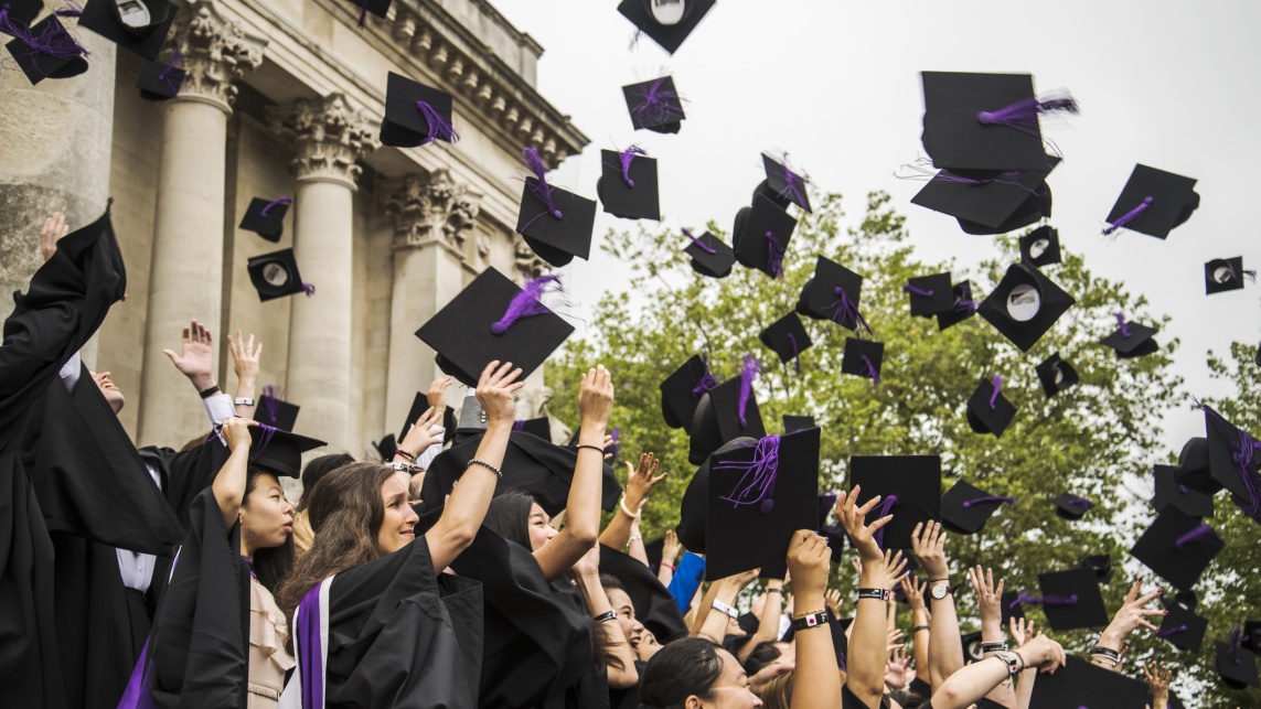 Students graduating throw their mortar boards into the air.