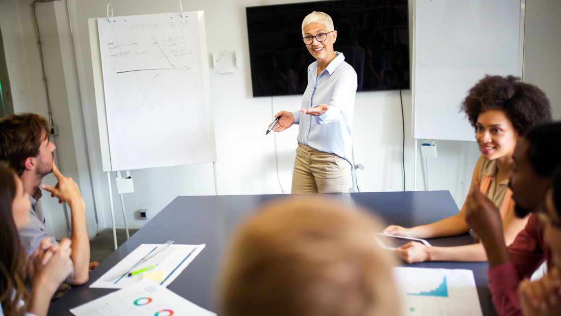 A lecturer teaches a small seminar group in a bright room 