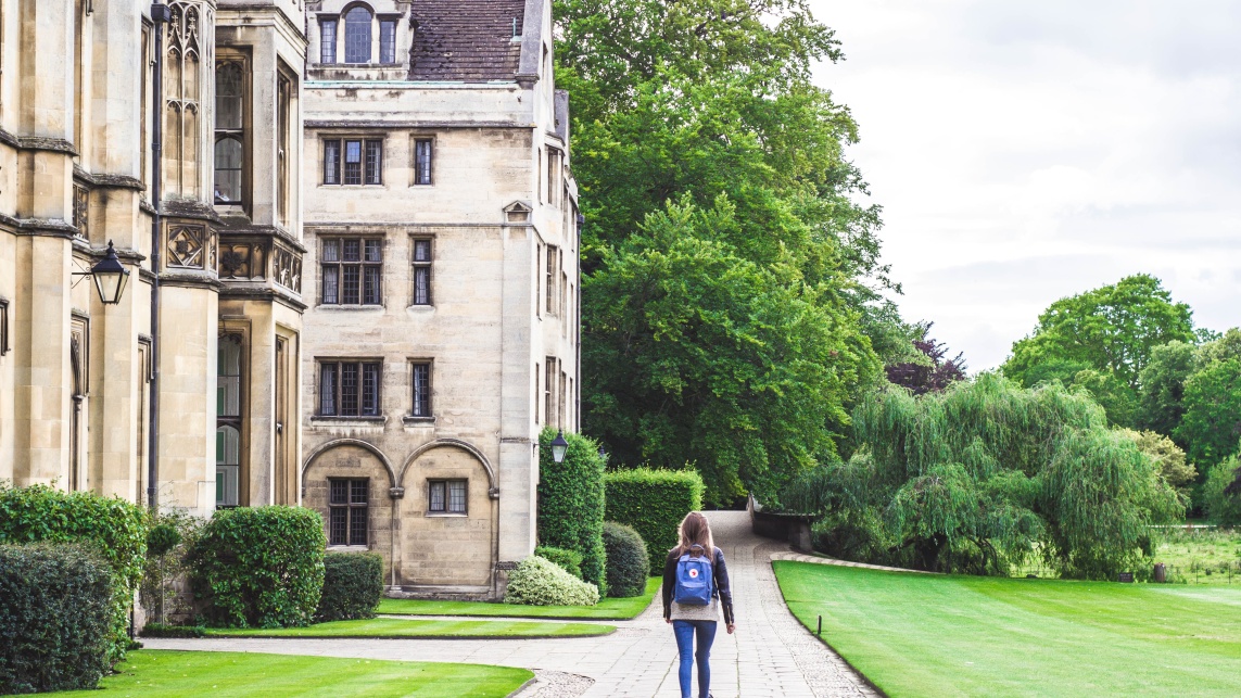 Student walking with a backpack next to a historic university building