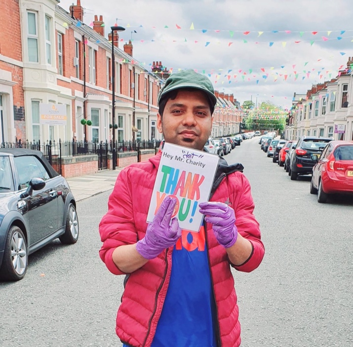 Mominul Hamid standing in a Newcastle street holding up a thank you card.
