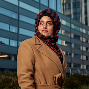 Dr Beenish Siddique standing outside with a modern university campus in the background