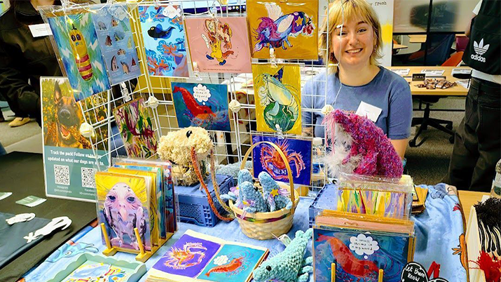 Amy Lovett, University of Plymouth student at her art stall with products displayed.