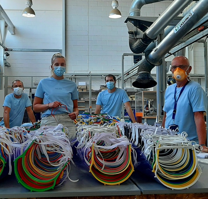 4 volunteers stand in front of the visors they have helped create 