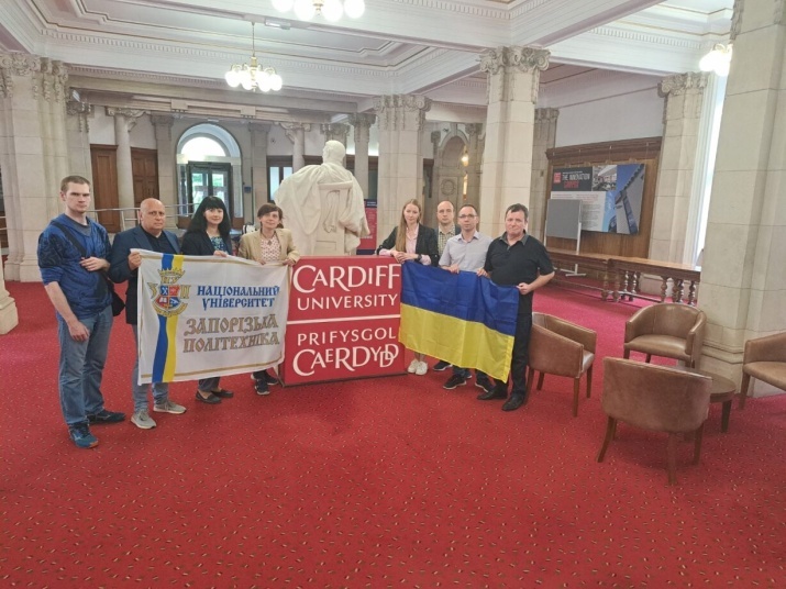 Colleagues involved in the Cardiff University and Zaporizhzhia Polytechnic National University Twinning partnership stand with banners displaying the Ukraine flag and logos for both universities.