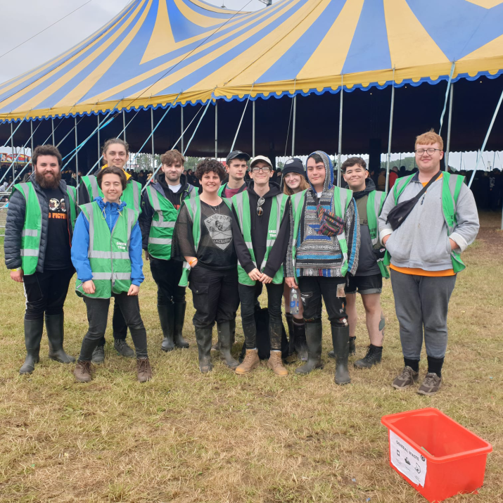 A group of students in front of a tent at a festival smiling 