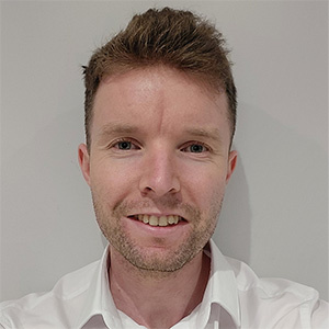 Harry Harrison standing in front of a white wall. Harry wears a white shirt.