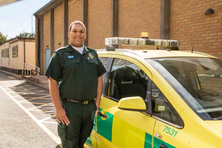 Obinna Okeke stands proudly in front of the ambulance he now works in.