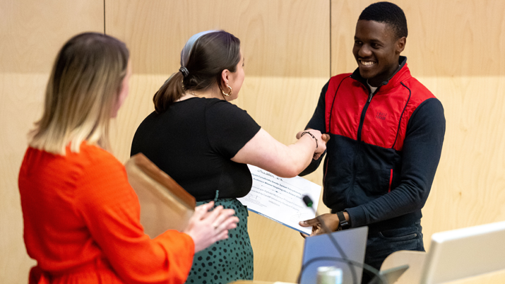 Horizun founder, Abdul Alim is accepting an award and shaking a woman's hand.