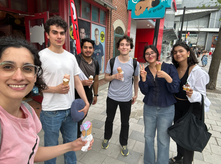 Zohra with five fellow Mitacs students, holding ice creams with shops in the background.