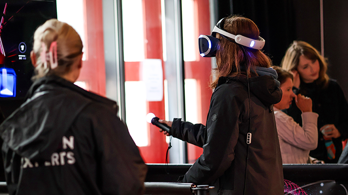 University of Bath Institute of Coding learners standing together. One participants is wearing a headset and holding a remote.